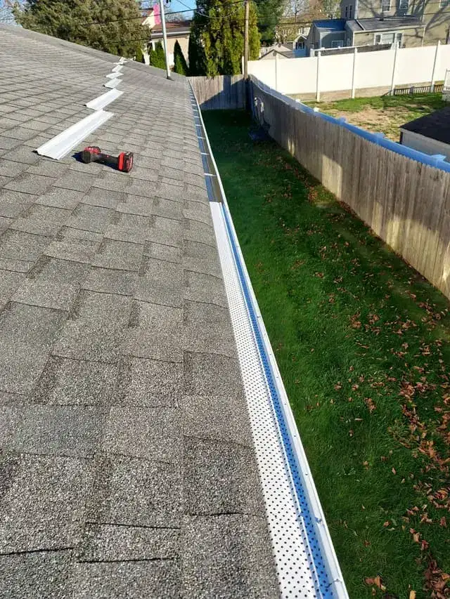 Asphalt shingle roof eave with gutter guard and ridge detail