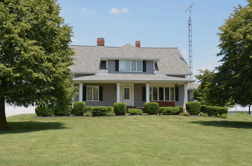 Two-story colonial home with a grey asphalt shingle roof, dormers, and brick chimneys