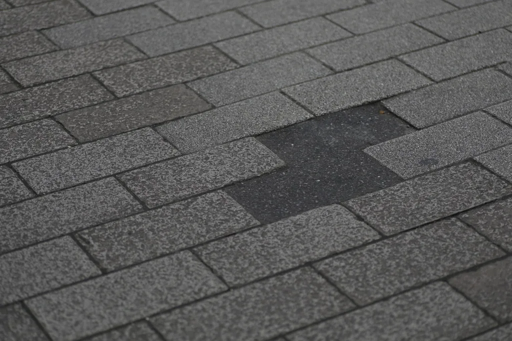 Asphalt shingle roof with a missing shingle tab exposing the underlayment beneath