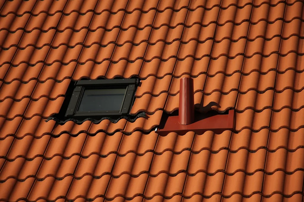 Vent pipe penetrating a roof slope with metal flashing sealing the opening